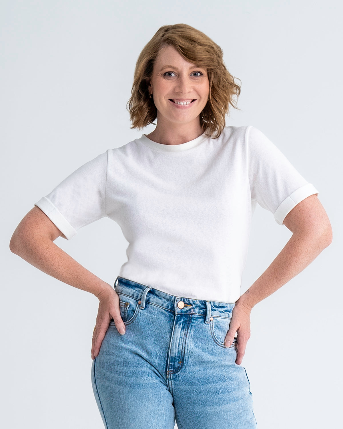 Front view of slim fit t-shirt in white, shown tucked into jeans. Model wears size 8.