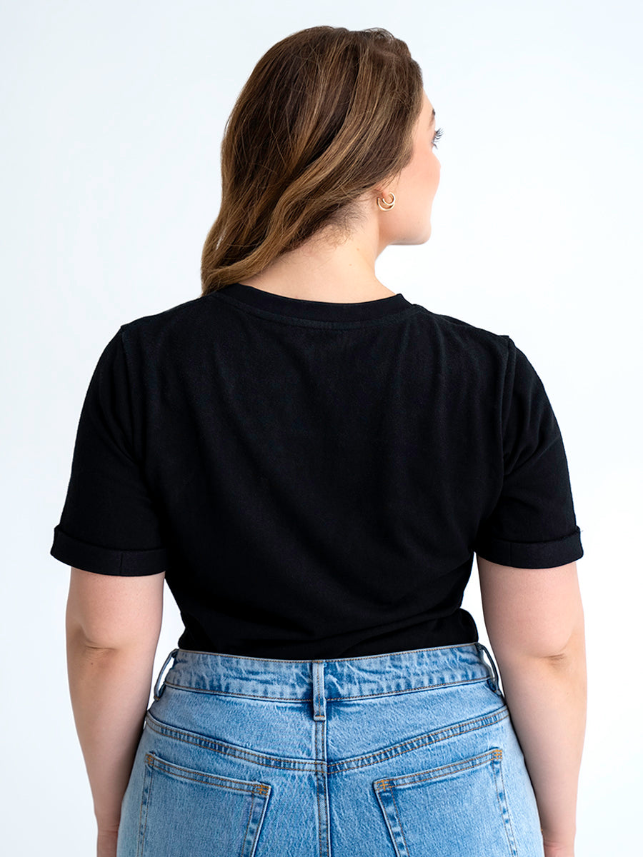 Back view of black t-shirt made for big boobs, shown tucked into jeans. Model wears size 12.