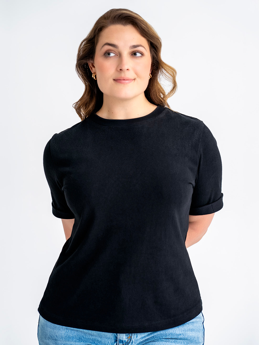 Front view of black t-shirt made for big boobs, shown untucked, finishes mid-hip. Model wears size 12.