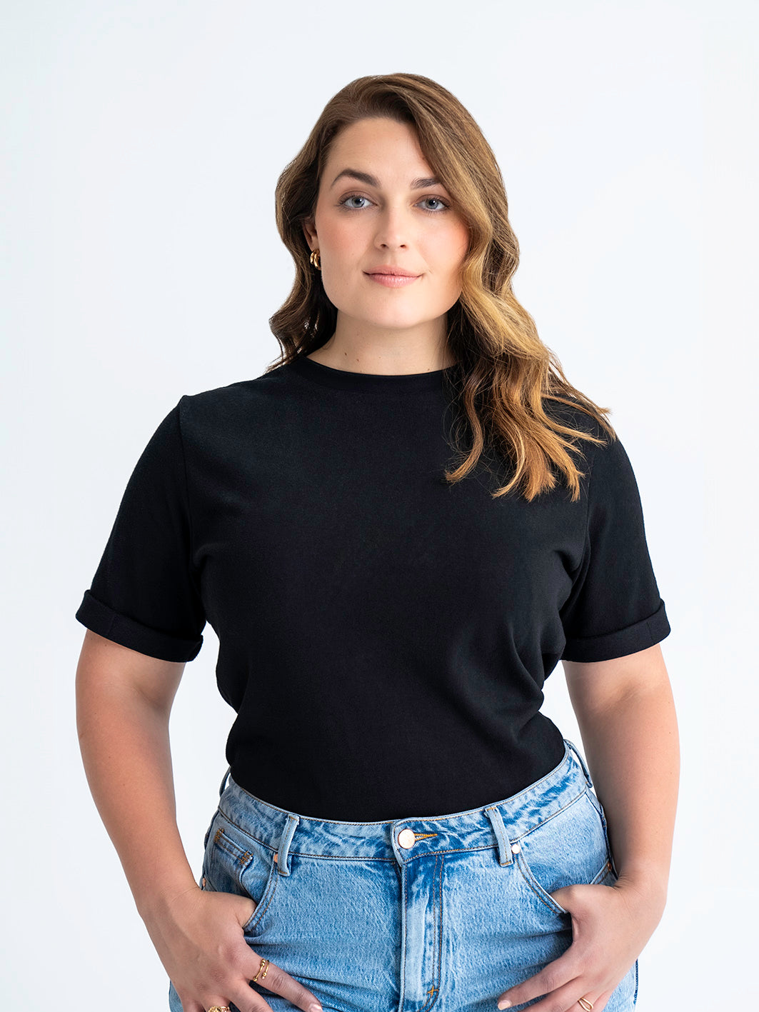 Front view of black t-shirt made for big boobs, shown tucked into jeans. Model wears size 12.