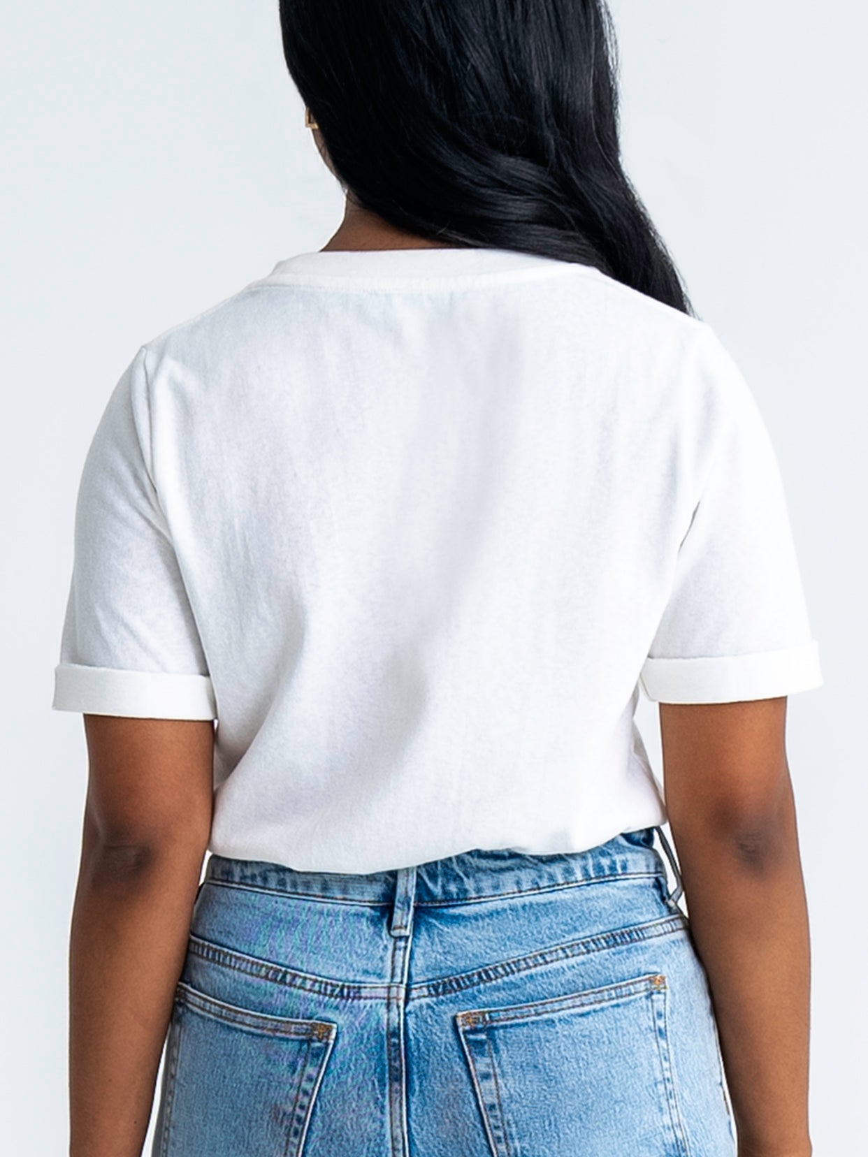 Back view of relaxed fit t-shirt in white, shown tucked into jeans. Model wears size 8.