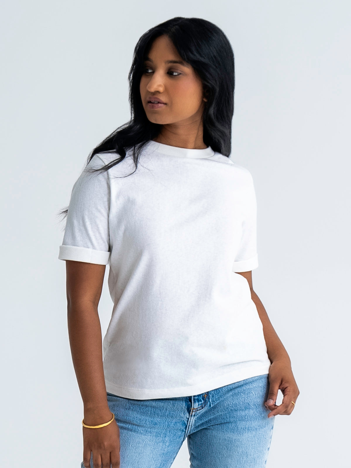 Front view of relaxed fit t-shirt in white, shown untucked, worn with jeans. T-shirt finishes mid-hip. Model wears size 8.