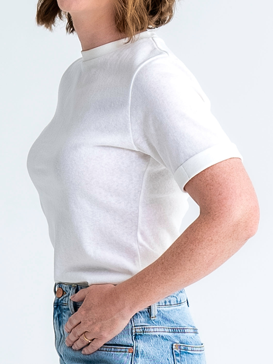 Cropped, side view of slim fit t-shirt in white, shown tucked into jeans. Model wears size 8.